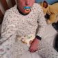 A Nipple Sucking Boy wearing the white suit is sitting on the bed.