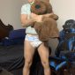A man holding Teddy, who is dressed in a white diaper and appears to be a baby boy,