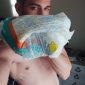 A man wearing a diaper is standing in the shadows.