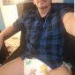 On the chair, a man in diapers is taking a picture.